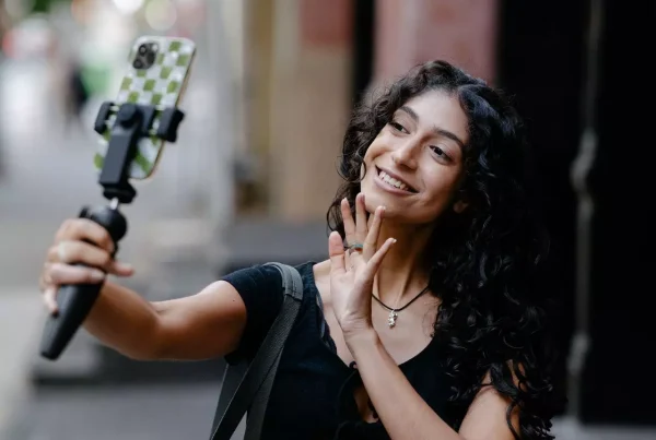Mujer con un palo de selfie grabandose en la calle como una influencer verdadera